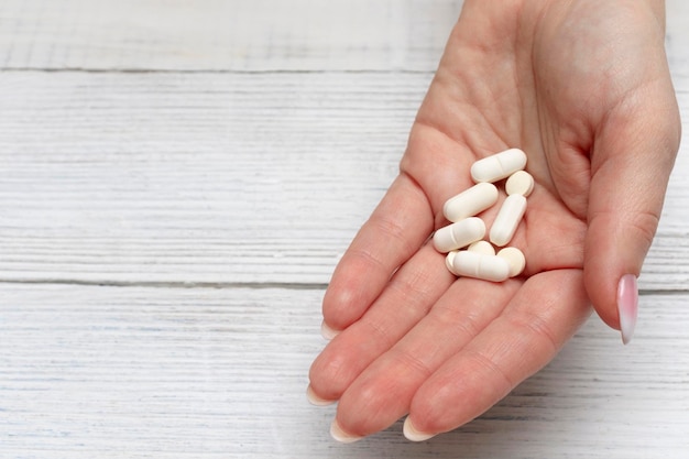 여성의 손에 있는 흰색 정제는 항생제 비타민 약을 복용한다는 개념입니다.