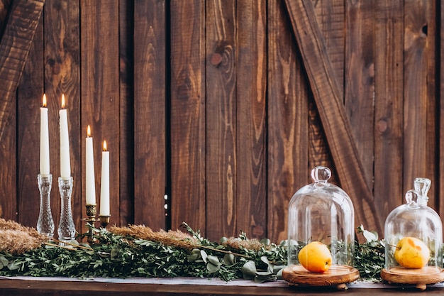 White tall candles in crystal candlesticks on  rustic wooden textured background.