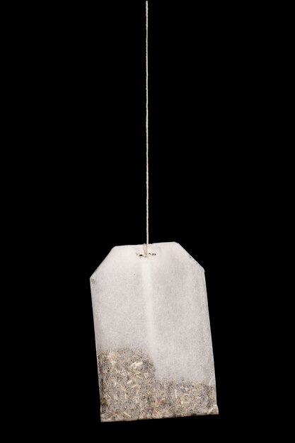 White tea bag on a rope isolated on a black background.