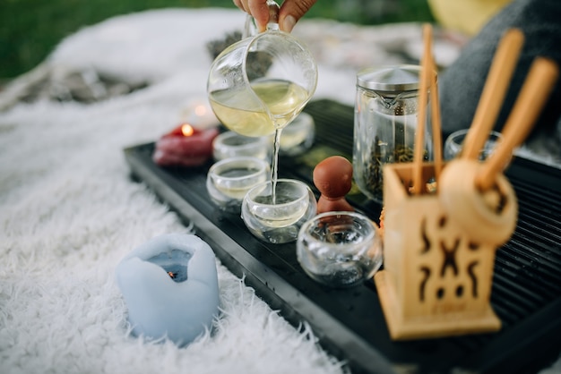 White tea is poured into glass cups close up Tea ceremony in the park