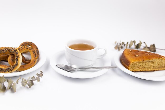 A white tea set with teapot tea and saucers and pie for breakfast
