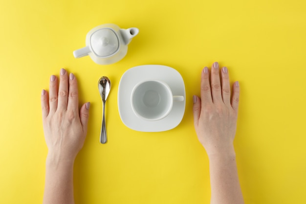 white teacup and teapot on yellow background