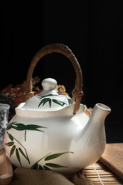 a white teapot with a leaf design on it