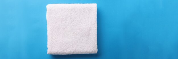 White terry towel is folded on blue background