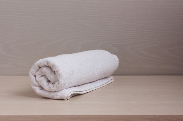 White Terry towel in a roll on the shelf.
