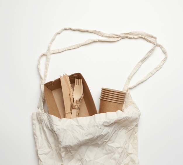 Photo white textile bag and disposable tableware from brown craft paper