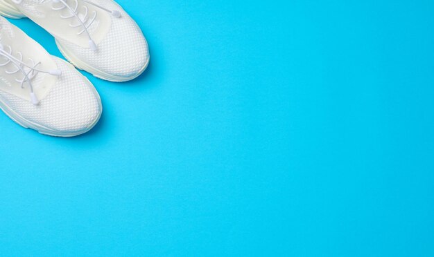 White textile sneakers on a blue background top view