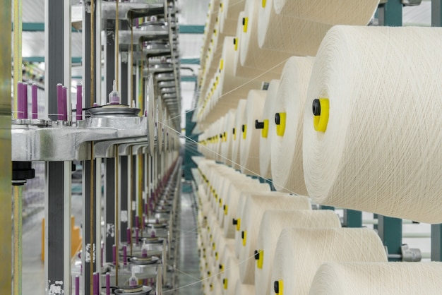 Photo white textile yarn on the warping machine. machinery and equipment in a textile factory