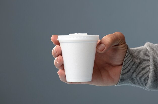 white thermal glass with lid in hand gray background