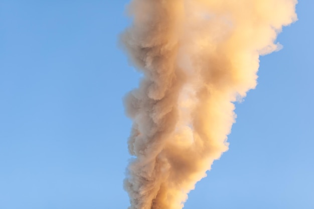 写真 ボイラー室の煙突から白く濃い煙。青い空を背景に煙します。大気汚染。