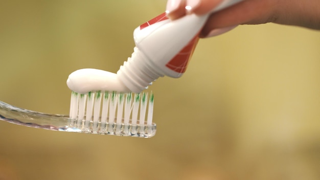 White toothpaste squeezing on toothbrush Woman hand holding toothbrush