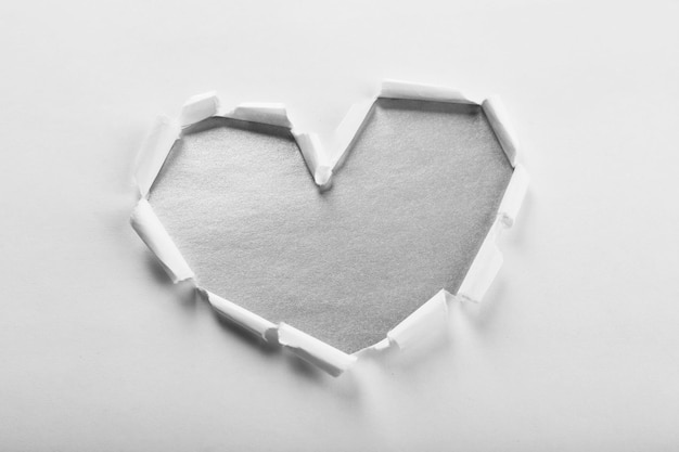 White torn paper heart over grey background