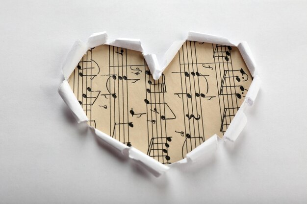 White torn paper heart over music background