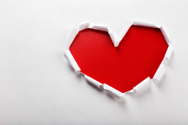 White torn paper heart over red background