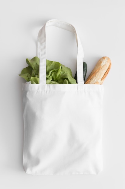 White tote bag mockup with groceries on a white table