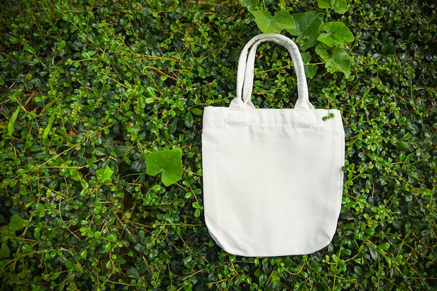 White tote canvas fabric eco bag cloth shopping sack on green leaf nature background