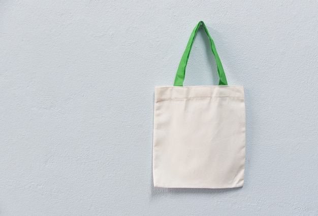 White tote canvas fabric eco bag cloth shopping sack on wall background 