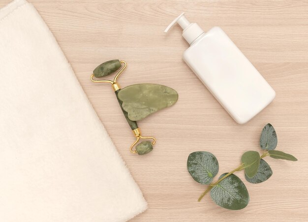 White towel and green jade roller White dispenser and eucalyptus branch