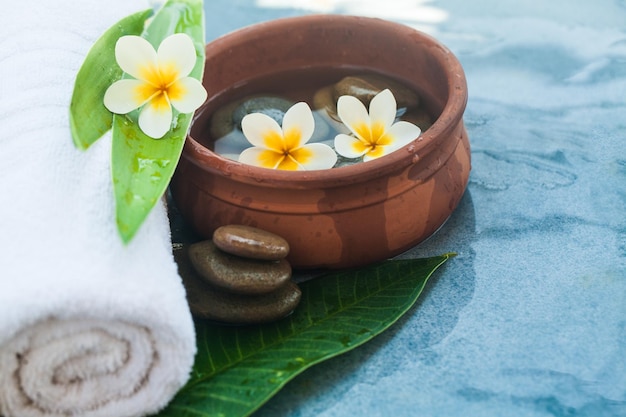 White towel Yellow flowers green leaves and cosmetics on blue marble background