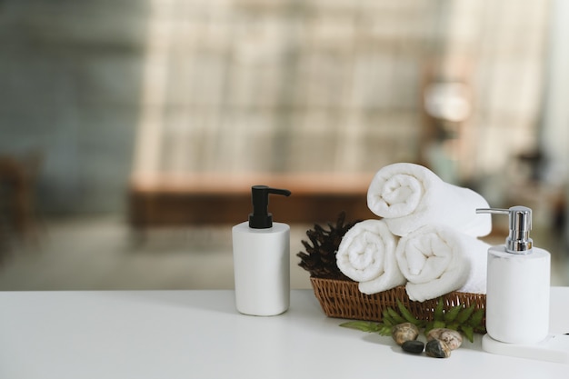 White towels and shampoo bottles on white table for relax spa massage and body treatment.