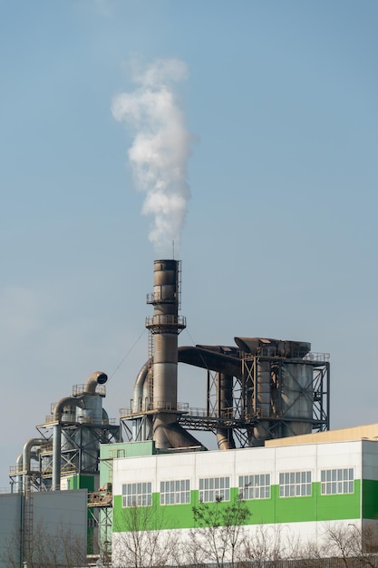 White toxic smoke comes out of factory chimneys environmental disaster and climate change on the planet Spraying of harmful substances into the atmosphere A working manufacture against a blue sky