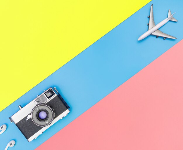 White toy plane and camera on blue and yellow pink background