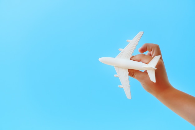 푸른 하늘에 대 한 아이의 손에 흰색 장난감 비행기