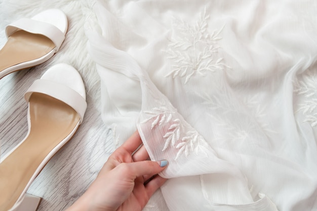 White transparent fabric in a female hand. White shoes. Fashionable 