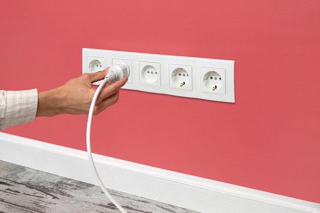 Photo white triple outlet installed on the pink wall side view