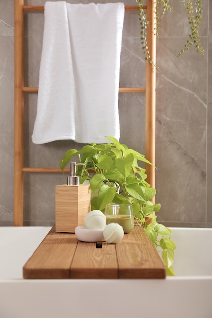 욕실 인테리어 디자인에 식물 비누 디스펜서와 목욕 폭탄이 있는 흰색 욕조