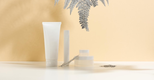 White tube for cosmetics a jar of cream and silver leaf on a white table Cosmetic on a beige shadow background Cream bottle lotion cleanser shampoo for skincare