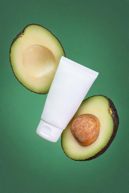 White tube of cream and avocado on a green background