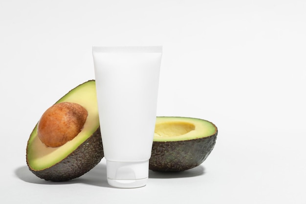 White tube of cream and avocado on a white background