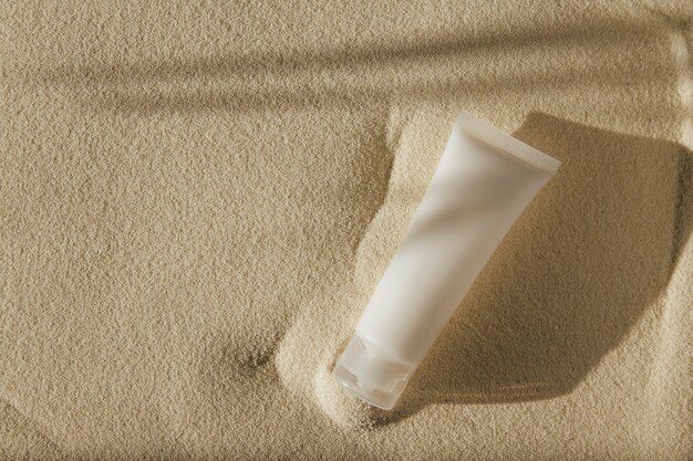 white tube with cream on sand background