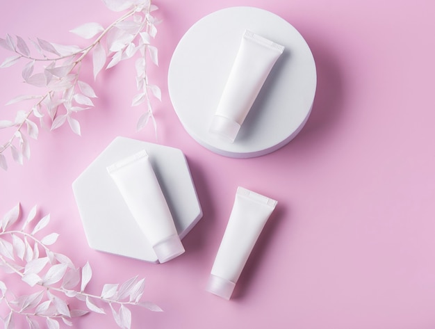 White tubes of cream on a pink wall