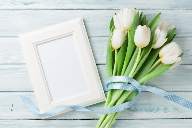 White tulips bouquet and blank photo frame