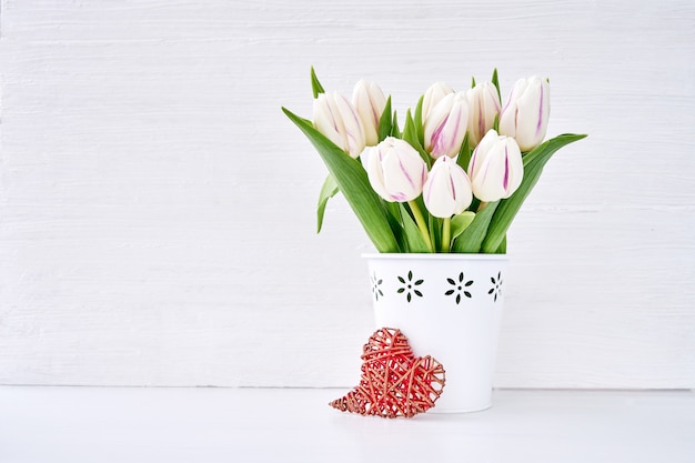 White tulips bouquet in white vase with red heart. Valentines Day, Wedding concept. Copy space