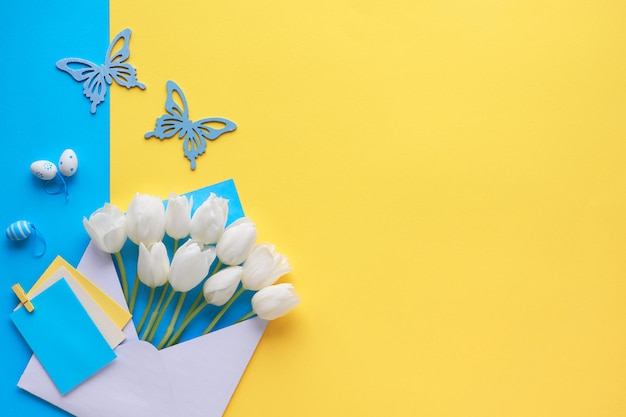 White tulips in envelope on paper background with Spring decorations