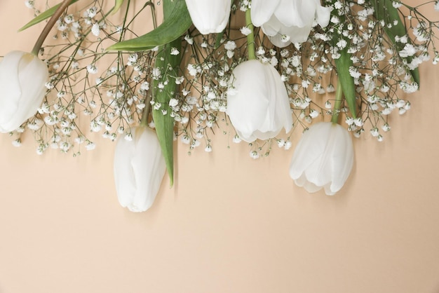 White tulips and gypsophila flowers bouquet on a beige background Mothers Day birthday celebration concept Copy space for text Mockup