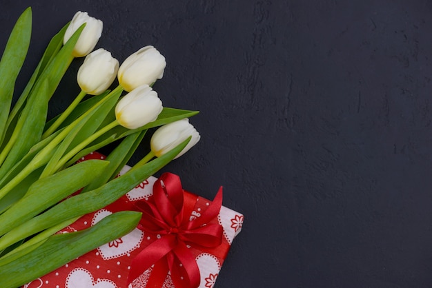 Foto tulipani bianchi e regalo rosso con stampa a cuore con copia spazio per i saluti