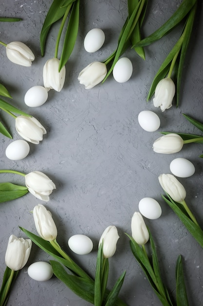White tulips with eggs on gray concrete background