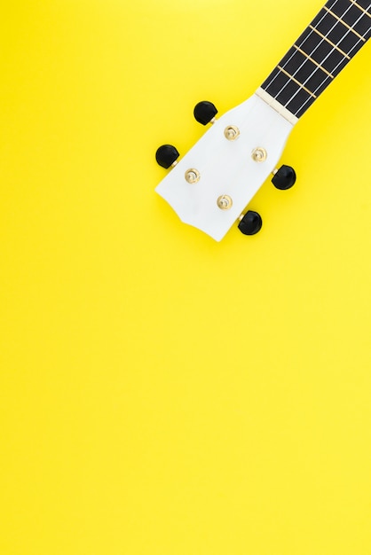 White ukulele on a yellow background and with a place for text. Musical concept. Flat Lay