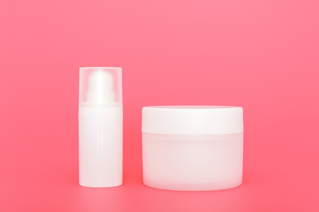 White unbranded cosmetic cream jars group. Skin care product presentation on the pink background. Trendy mockup. Skincare, beauty and spa.