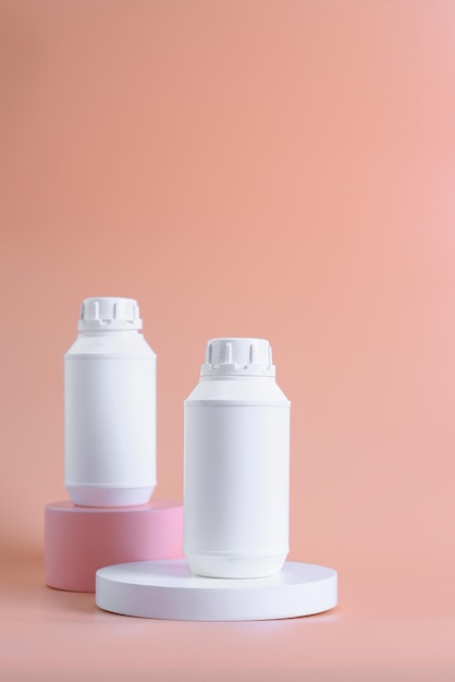브랜드가 없는 흰색 플라스틱 약병은 다시 분홍색과 흰색 연단에 비타민이나 알약을 흉내냅니다.