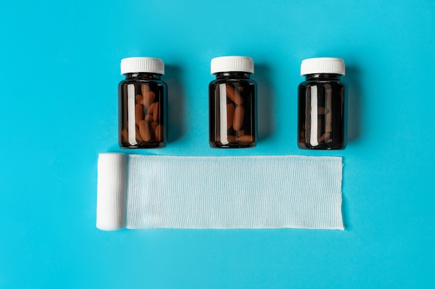 Photo white untwisted gauze bandage with three brown transparent jars for tablets on a blue .health .