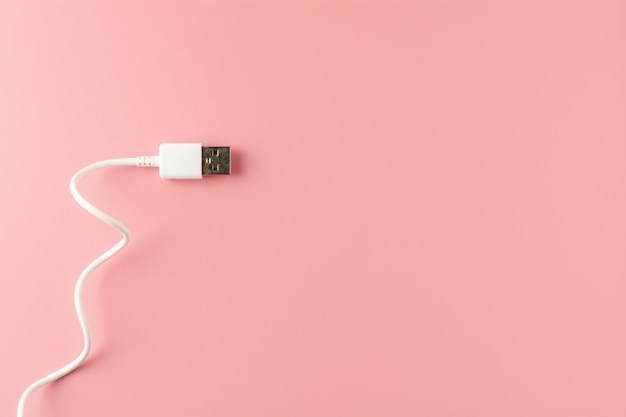 White USB cable on pink background.