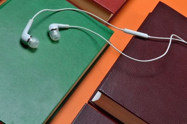 White vacuum earphones lie on books laid out. audiobook concept.