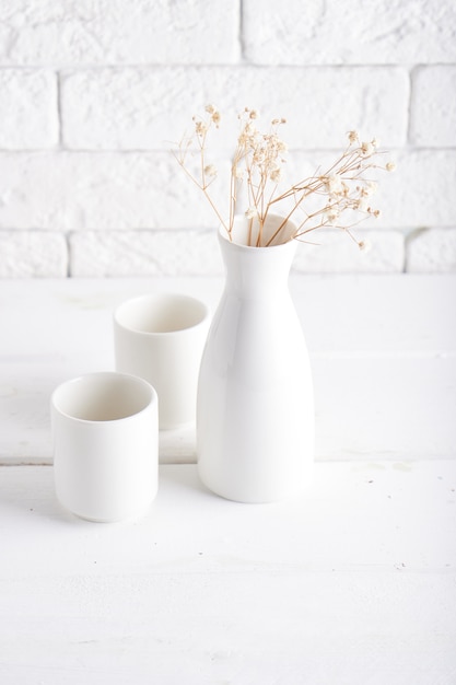 White vase and cups on a white table Copy space Vertical