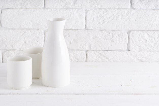 White vase and cups on a white table Copyspace