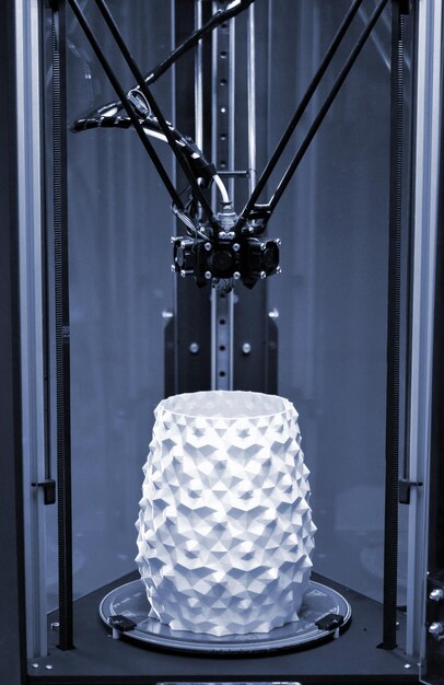 A white vase is standing inside a 3d printer